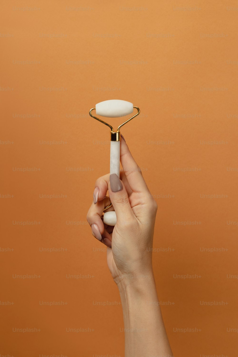 a hand holding a toothbrush in front of an orange background