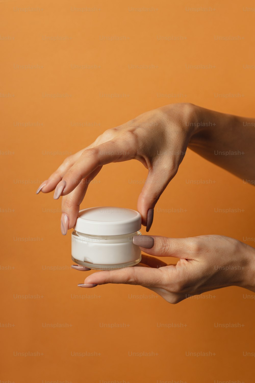 Une femme tenant un pot de crème dans ses mains