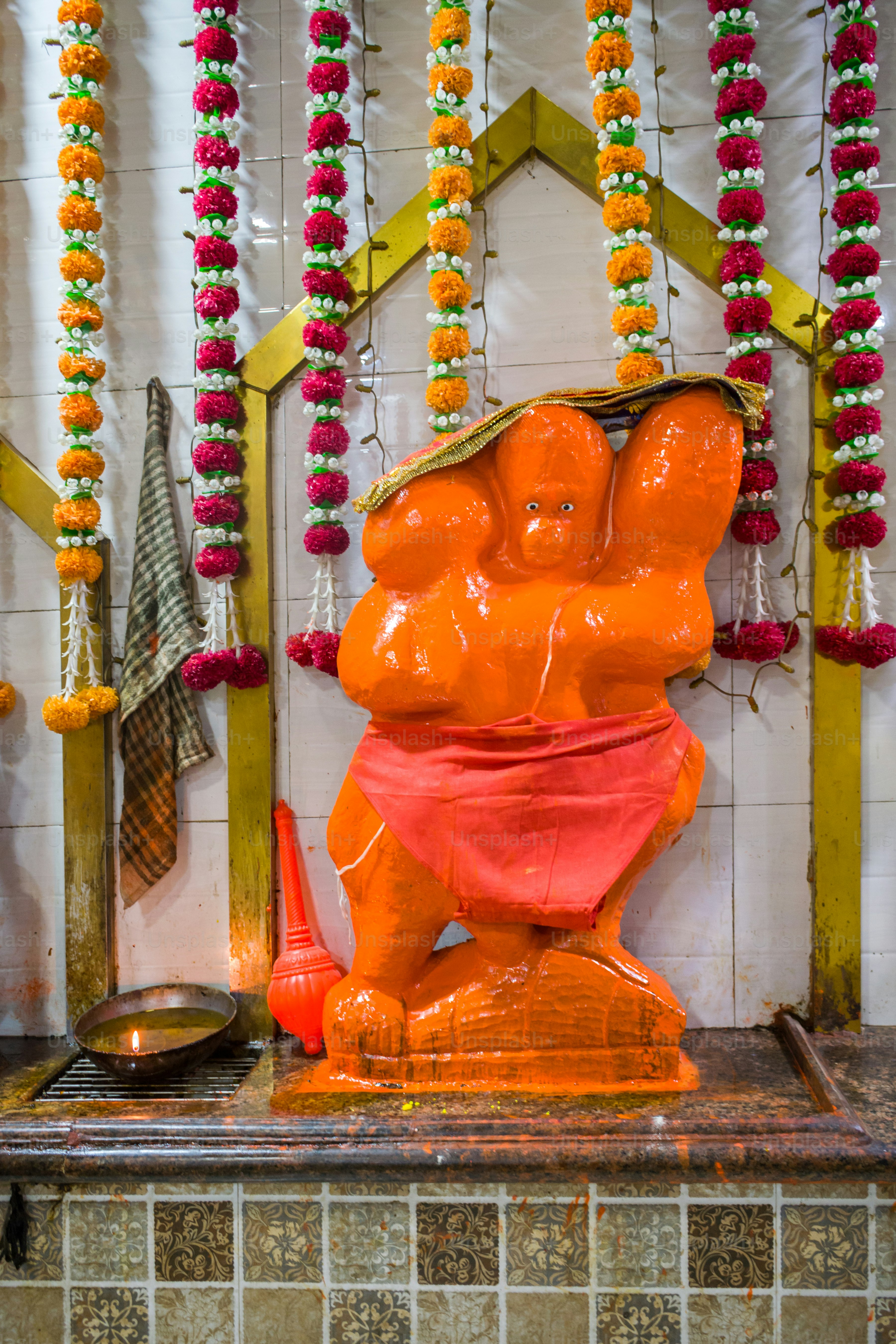uma estátua de um urso laranja na frente de uma parede de flores