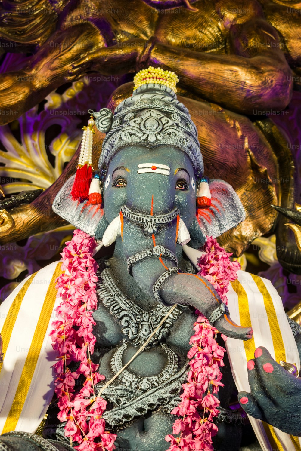 a statue of an elephant with flowers around its neck