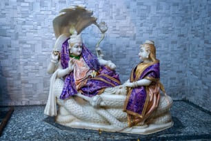 Una statua di una donna seduta su un letto accanto a un uomo