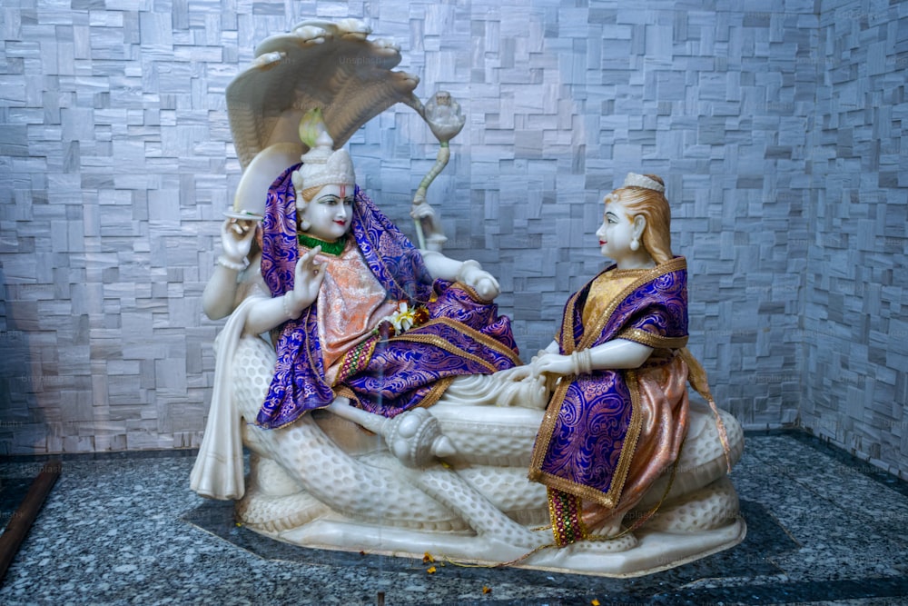 a statue of a woman sitting on a bed next to a man