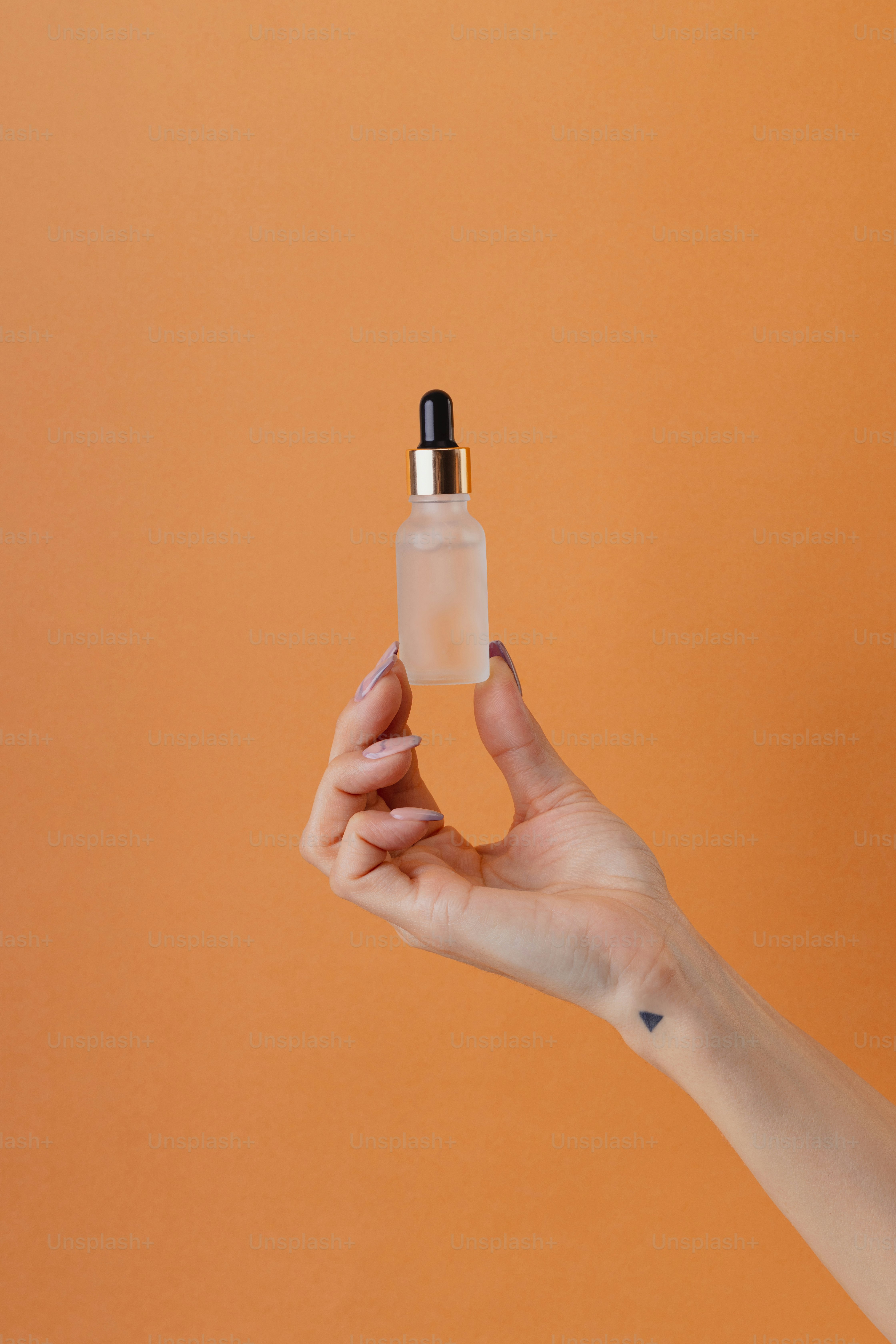 a hand holding a small bottle of liquid