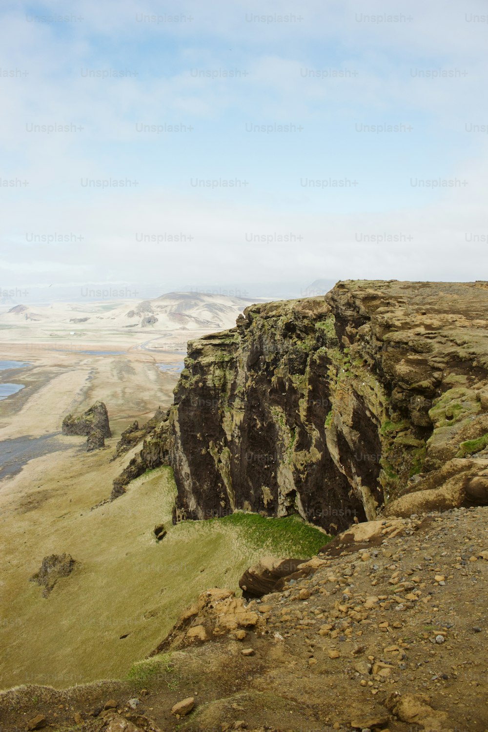 a rocky cliff with a body of water in the distance