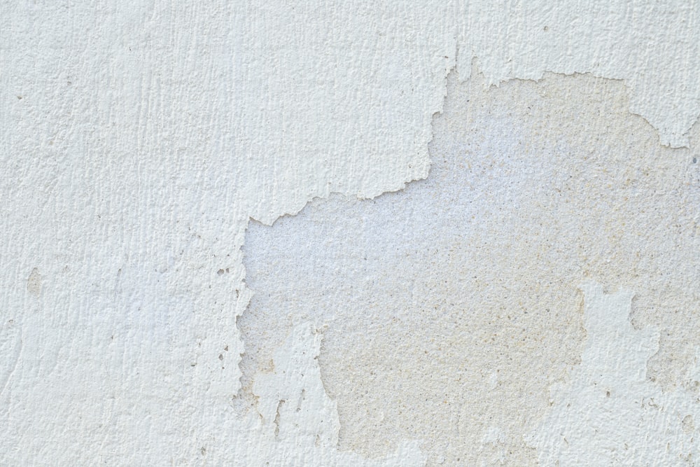 un gros plan d’un mur blanc avec de la peinture écaillée