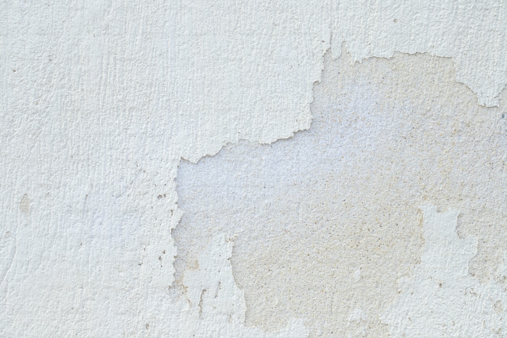 a close up of a white wall with peeling paint