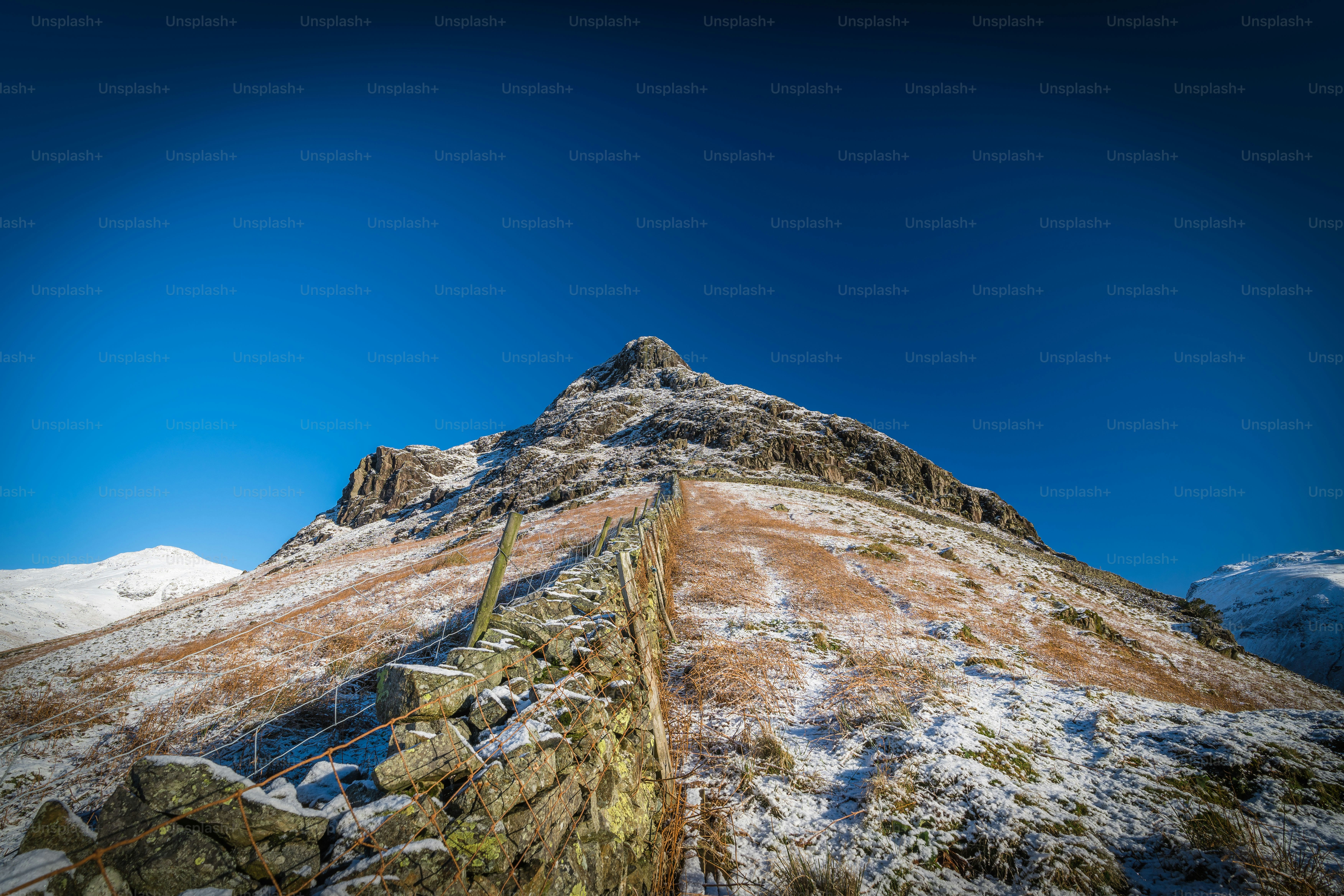 a very tall mountain covered in snow under a blue sky