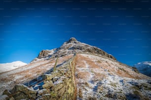 a very tall mountain covered in snow under a blue sky