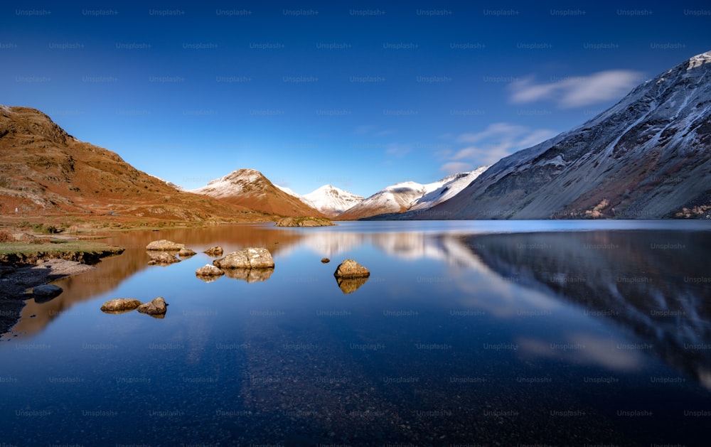 a lake surrounded by mountains under a blue sky