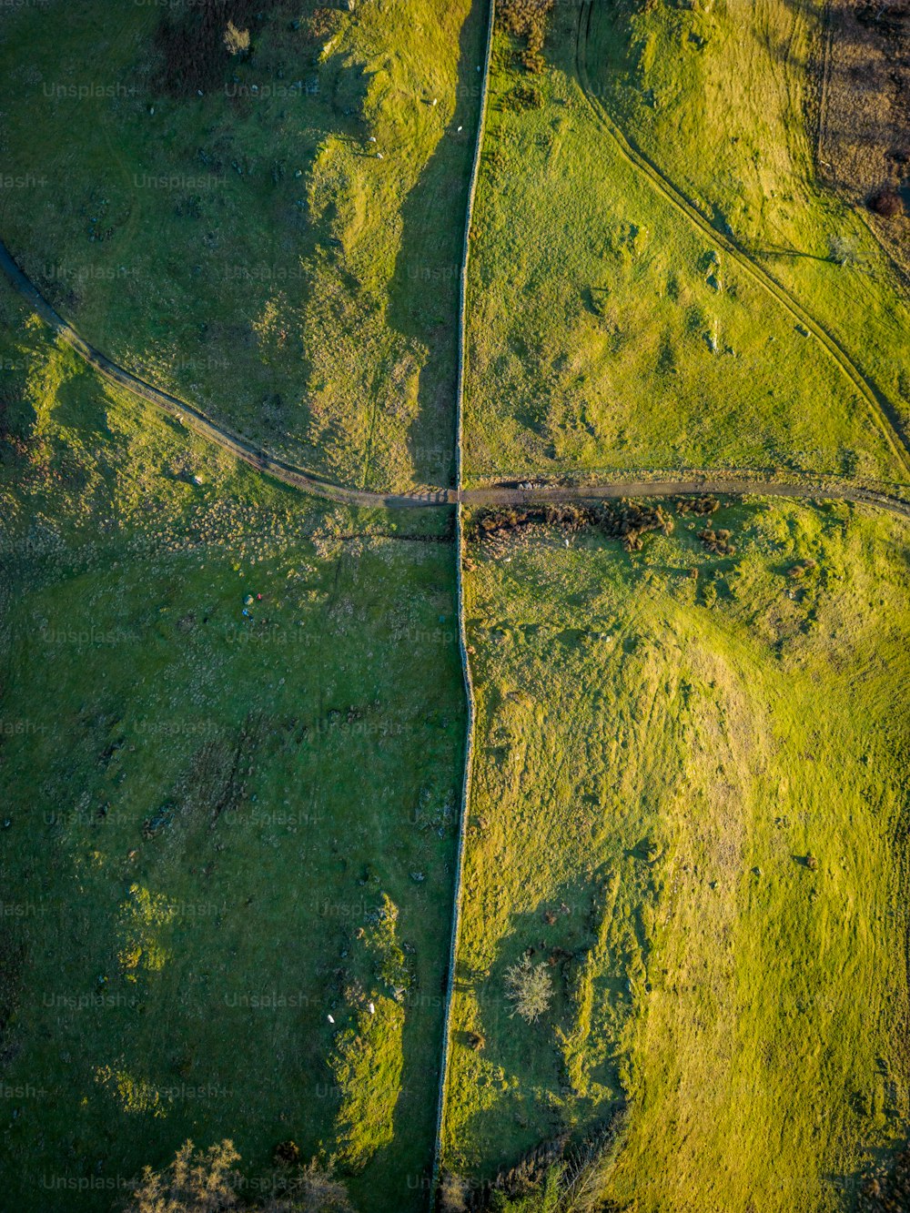an aerial view of a grassy field with a train track