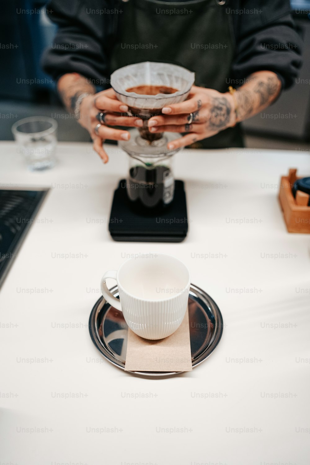 a man holding a cup of coffee on top of a white table