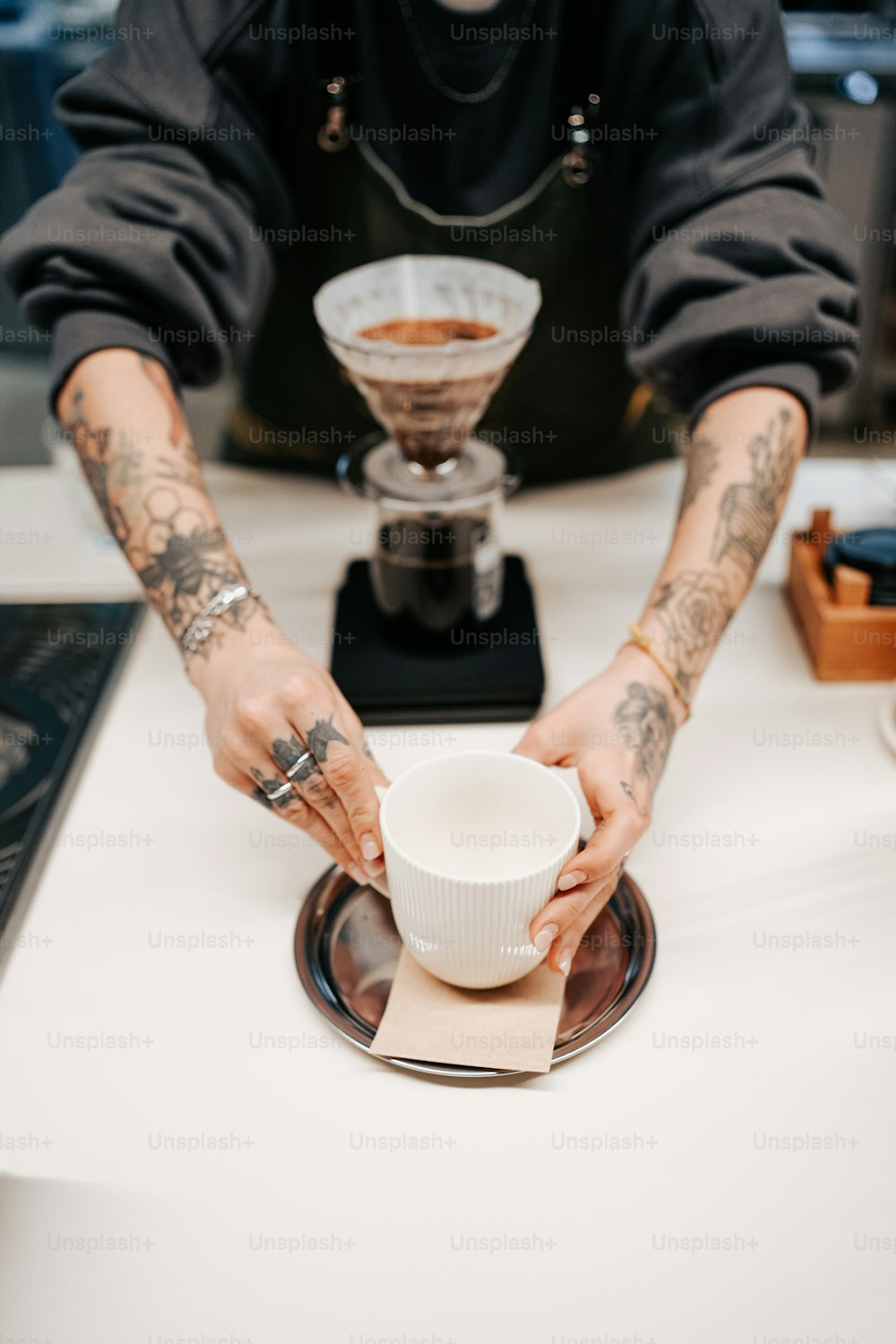 a man with tattoos on his arms holding a coffee cup