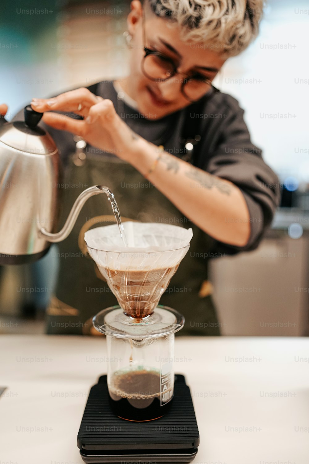 a woman pours coffee into a glass cup
