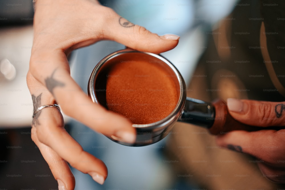 um close up de uma pessoa segurando uma xícara de café