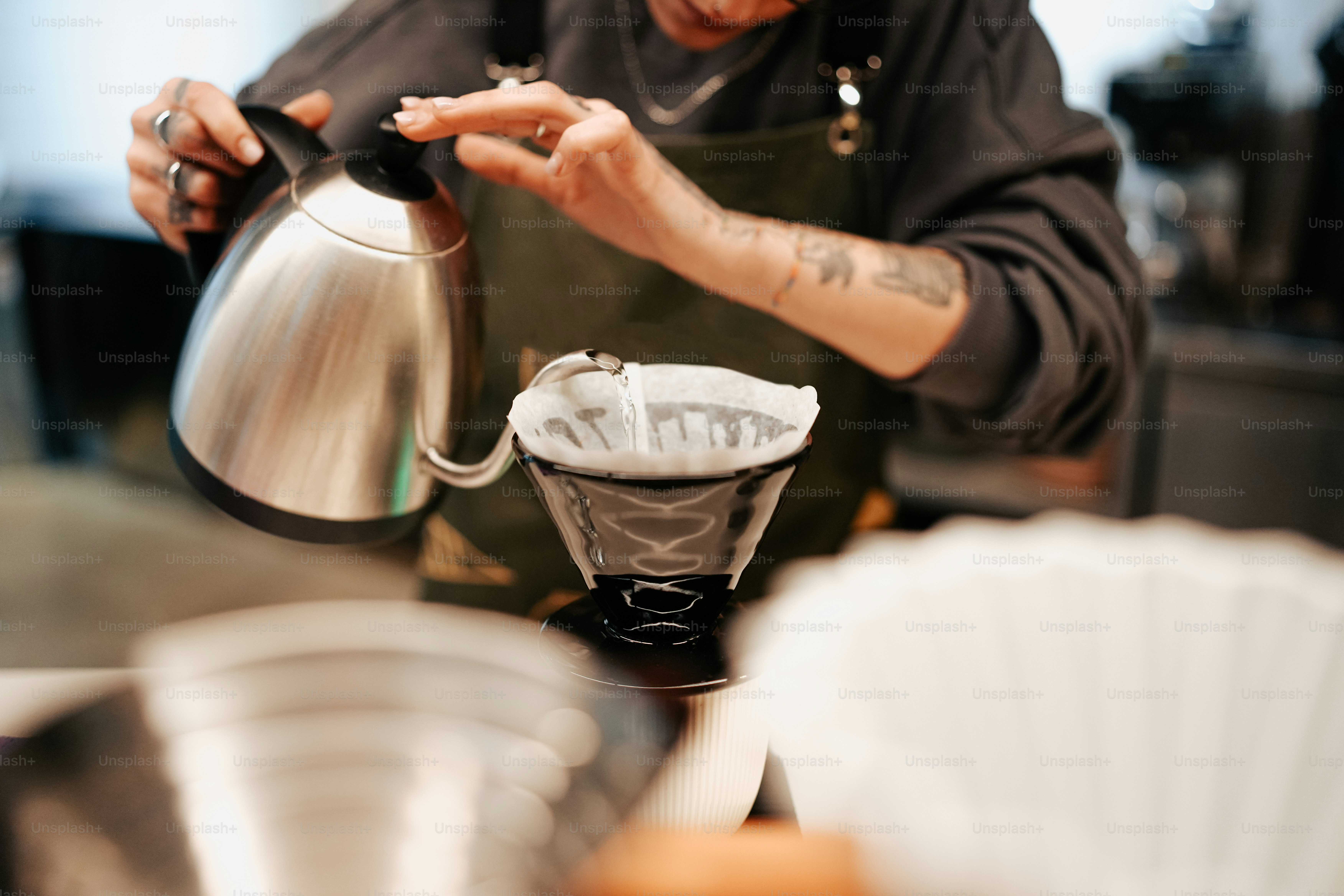 Ein Mann gießt eine Tasse Kaffee in ein Sieb