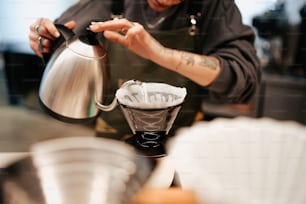 Ein Mann gießt eine Tasse Kaffee in ein Sieb