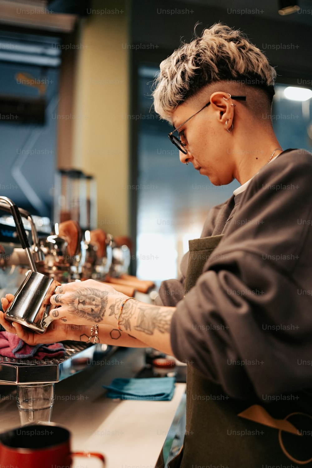 Eine Frau mit einem Tattoo auf dem Arm füllt eine Tasse Kaffee
