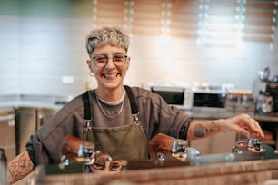 a woman in an apron is filling glasses at a counter