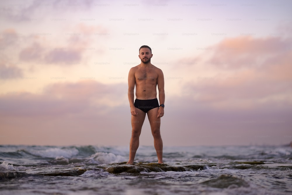 a man standing on top of a rock near the ocean