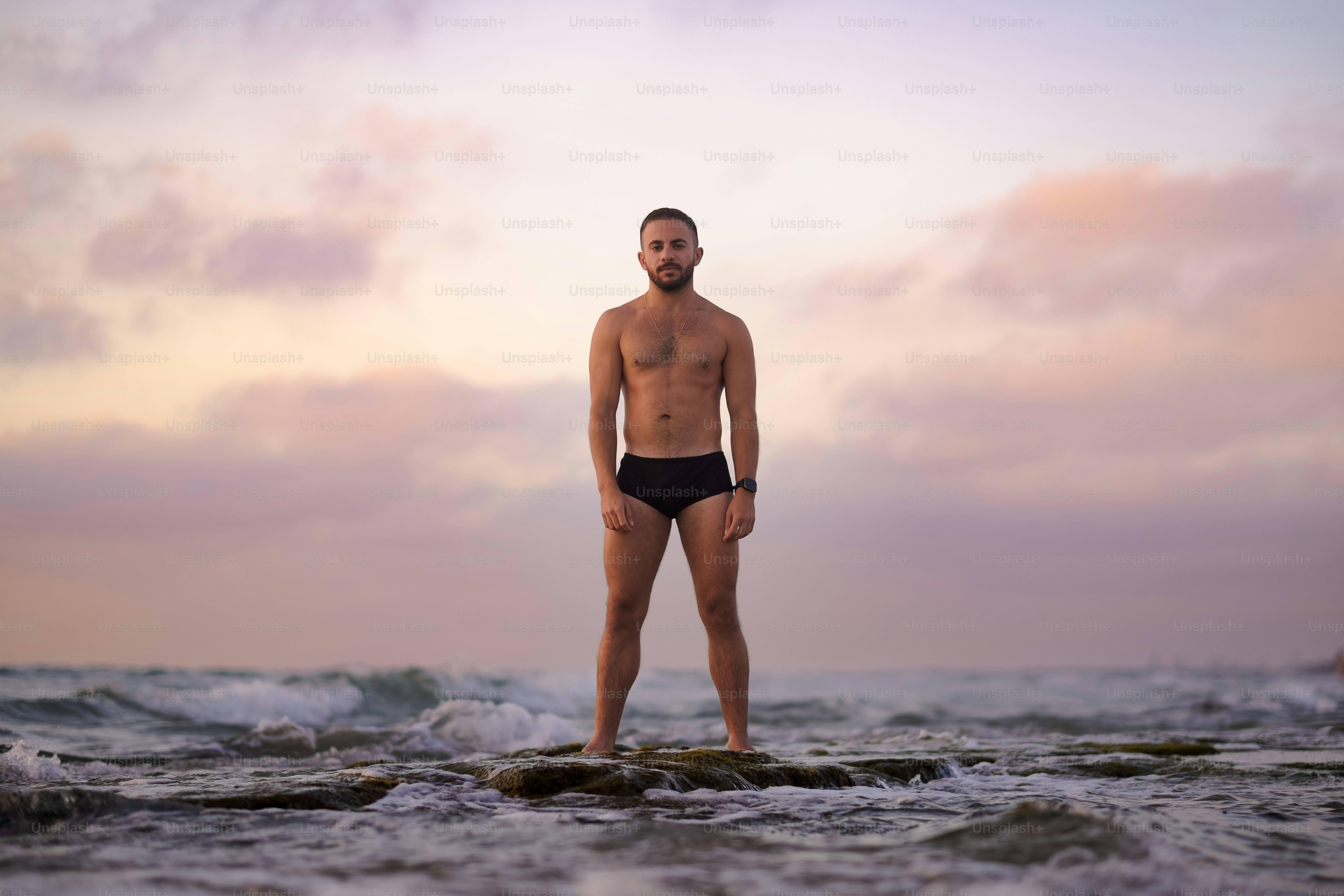 Amid the splashing waves, a man in swimwear expresses a joyful, affirmational narrative about his self-improvement and fitness journey.