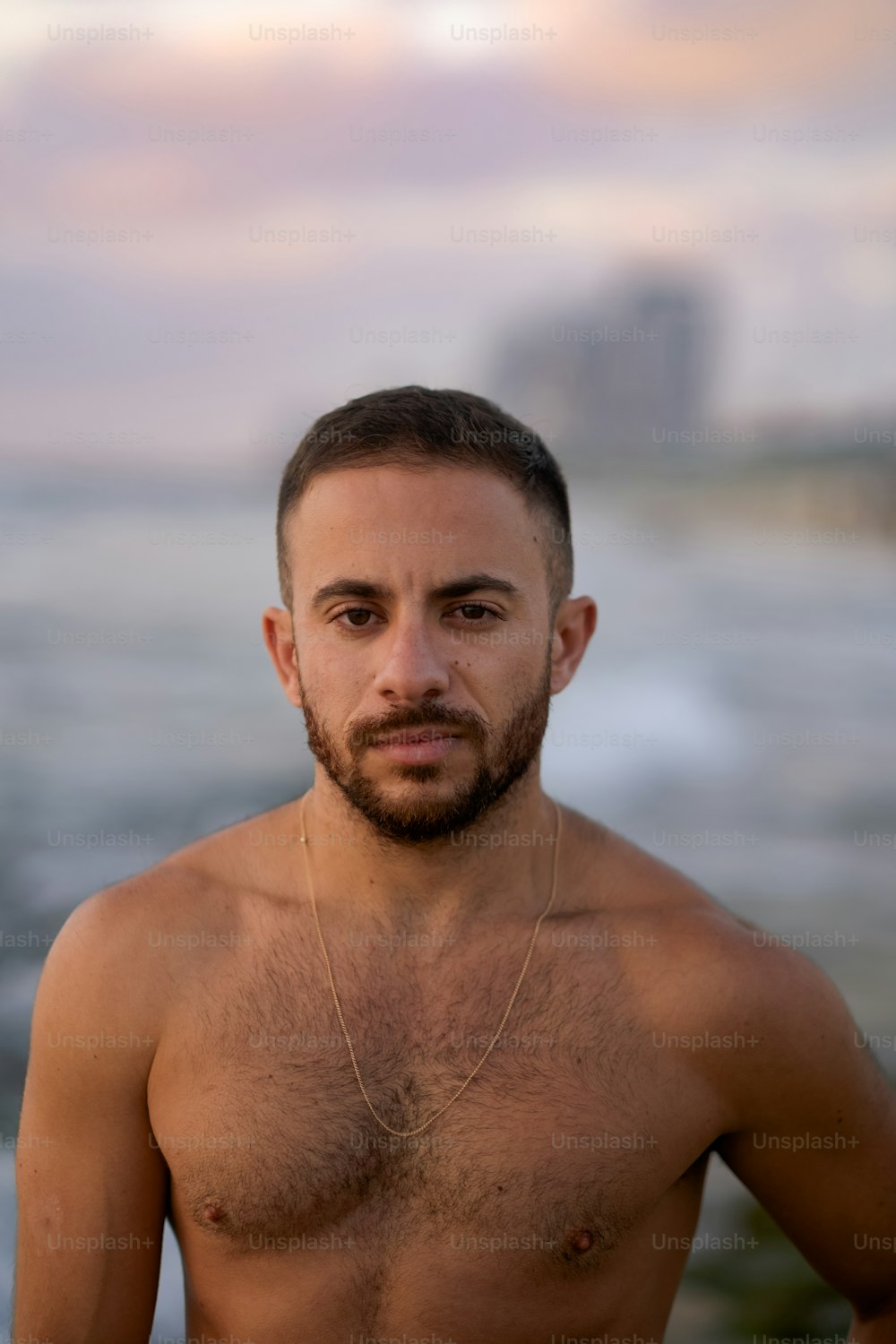 a shirtless man standing in front of the ocean