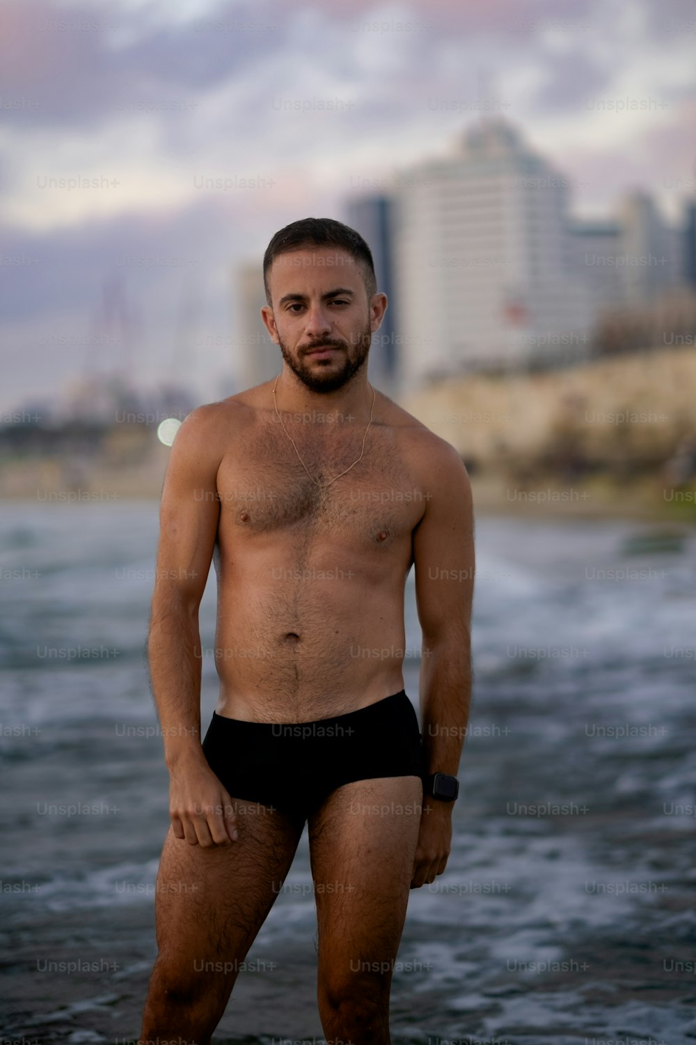 Un uomo a torso nudo in piedi nell'acqua di fronte a una città