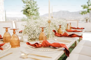 a table set for a formal dinner with red napkins