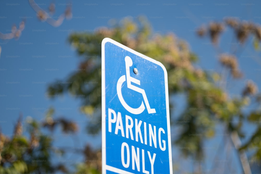 a blue parking only sign with trees in the background