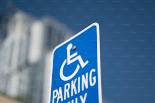 a blue parking only sign with a building in the background