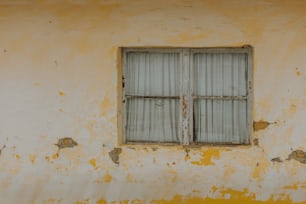 a yellow wall with a window and bars on it