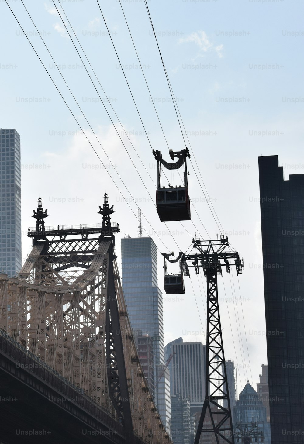 a cable car going over a bridge with a city in the background