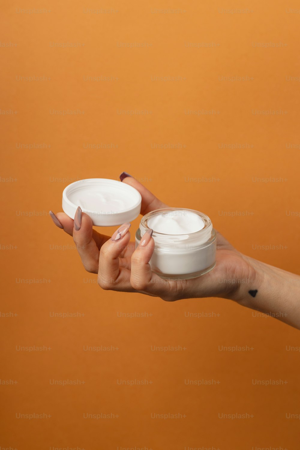 Una mujer sosteniendo dos recipientes de crema en sus manos