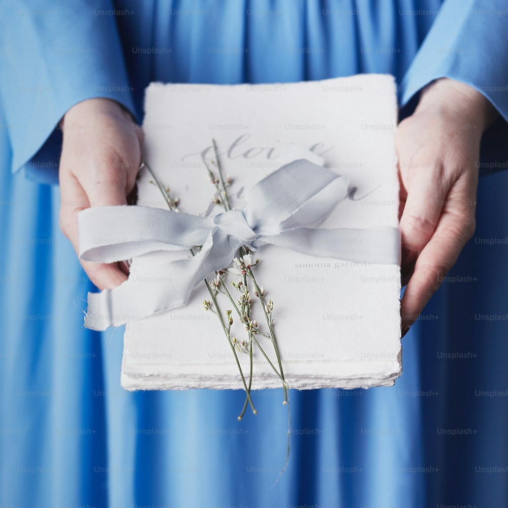 uma pessoa em um vestido azul segurando uma caixa branca