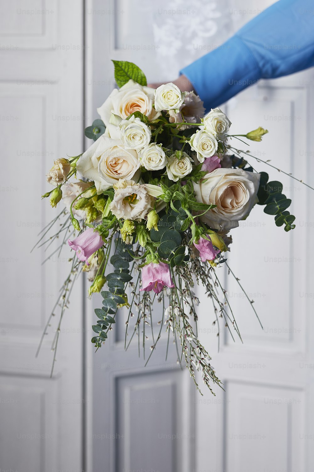 a person holding a bouquet of white and pink flowers