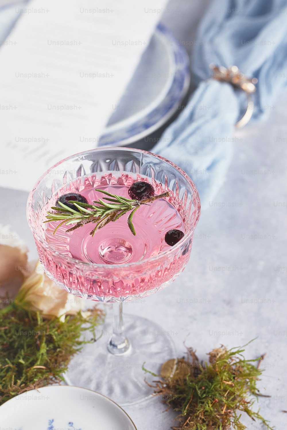a pink drink with a sprig of rosemary in it