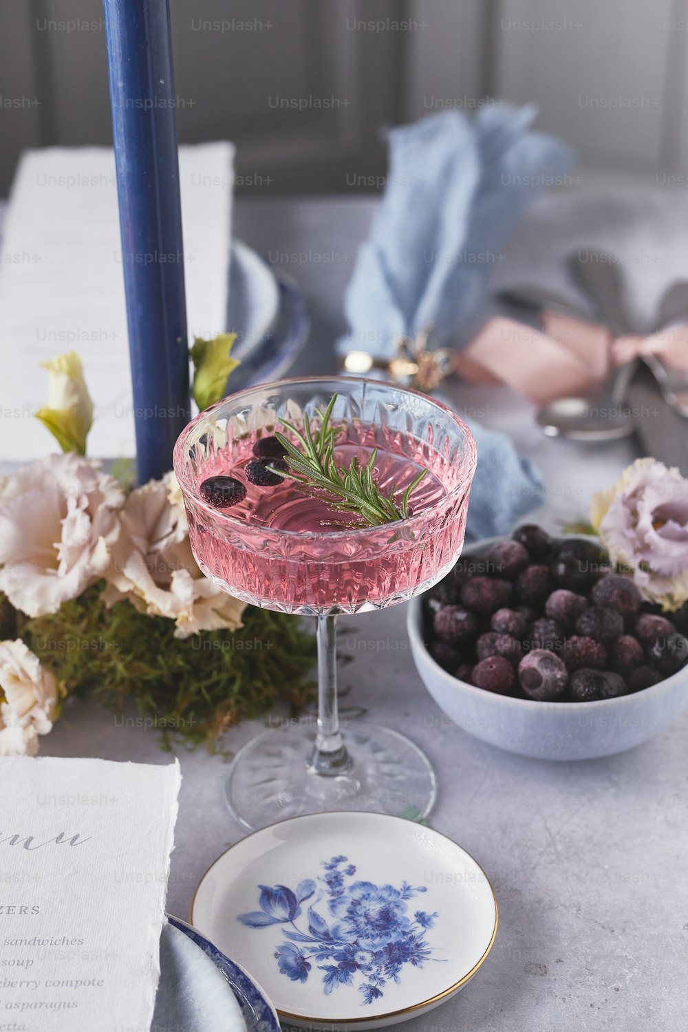 a table topped with a bowl of berries and a glass of wine