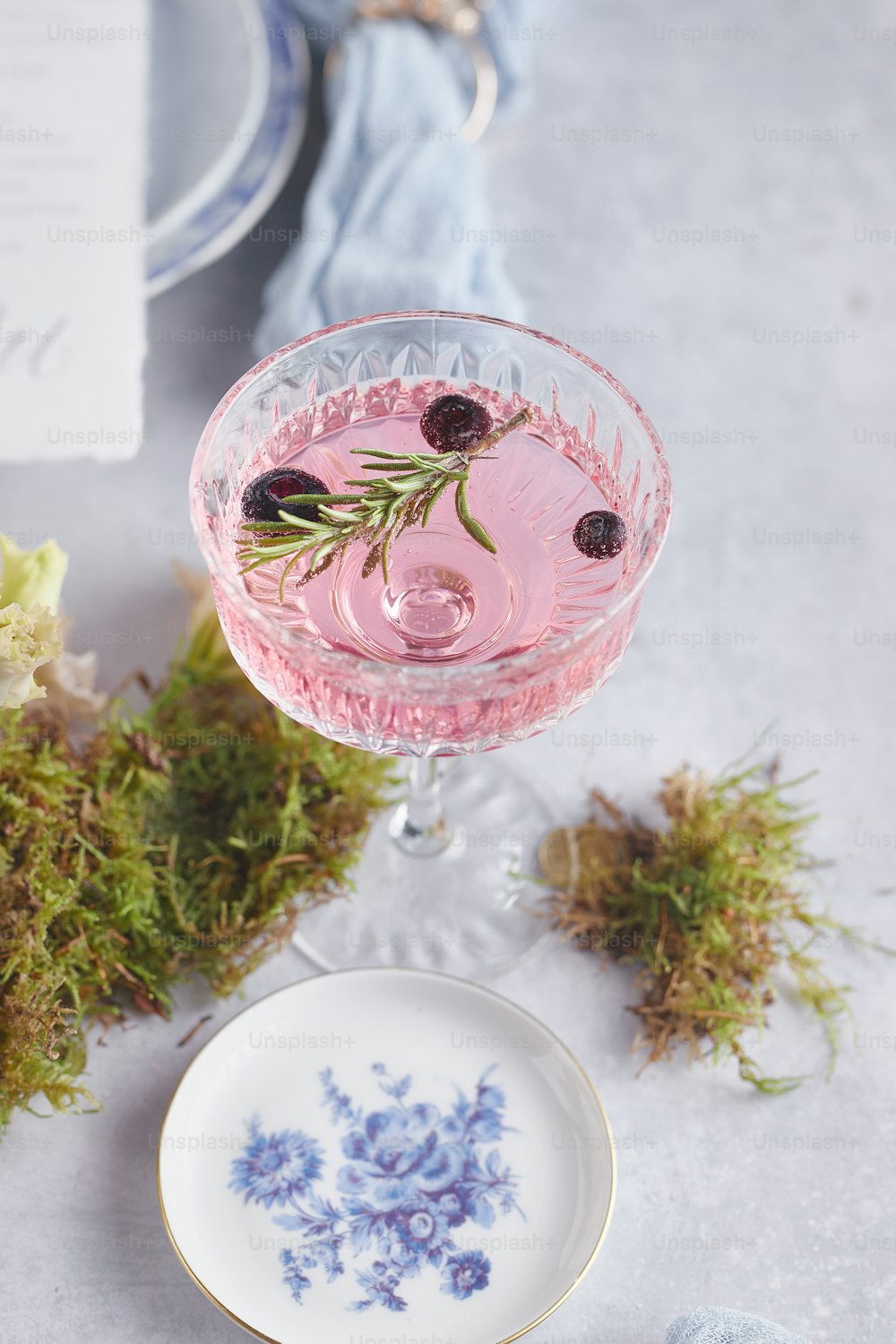 a pink drink with a sprig of rosemary in a glass