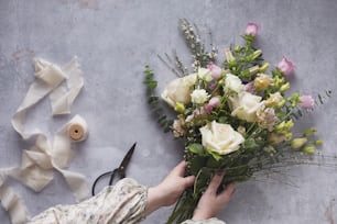 une personne tenant un bouquet de fleurs à côté d’une paire de ciseaux