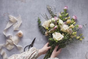 a person holding a bouquet of flowers next to a pair of scissors