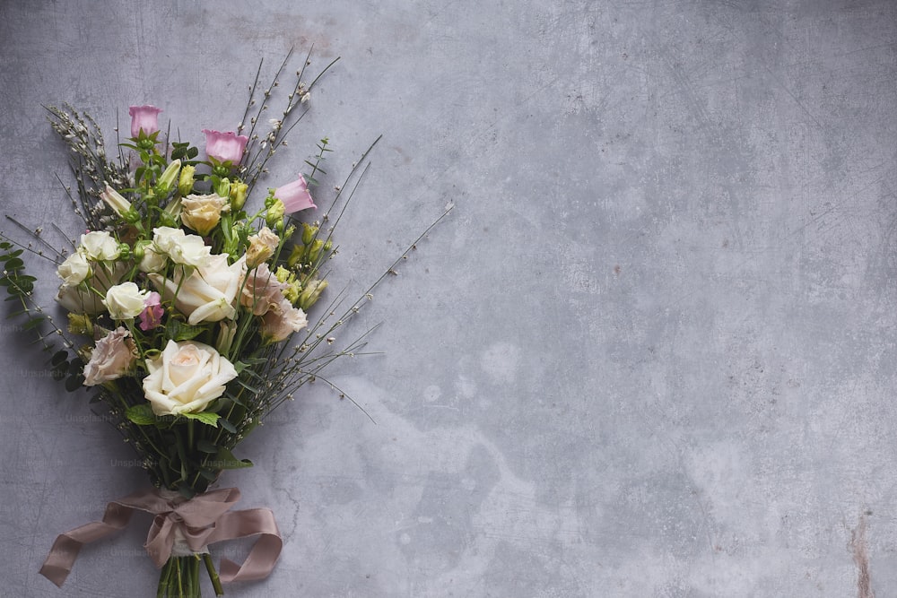 un bouquet di fiori bianchi e rosa su uno sfondo grigio
