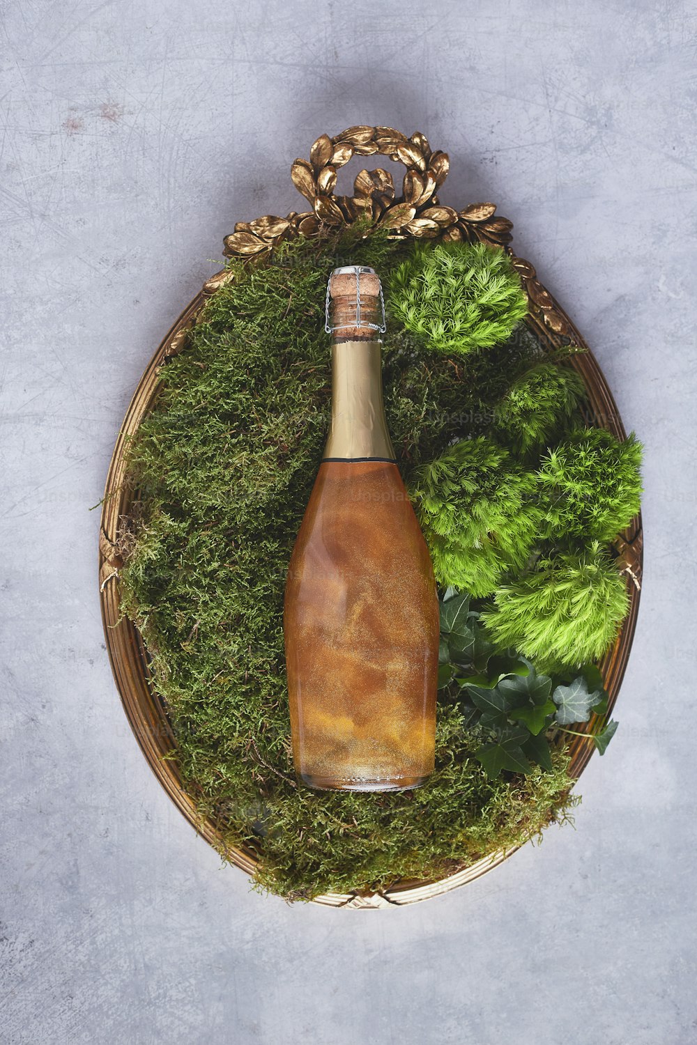 a bottle of wine sitting on top of a moss covered tray