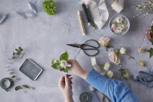 Una persona cortando flores con tijeras en una mesa