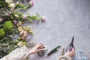 a person holding a pair of scissors next to flowers