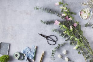 una mesa con flores, tijeras y otros artículos