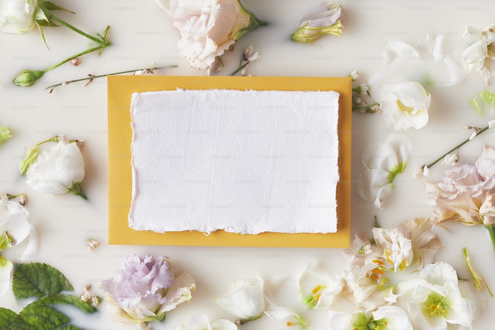 Un pedazo de papel encima de un marco amarillo rodeado de flores