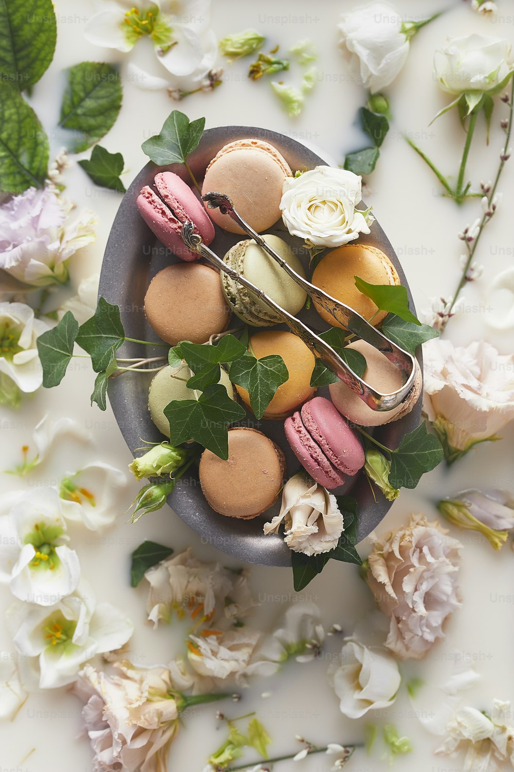 a bowl of macaroons and flowers on a table