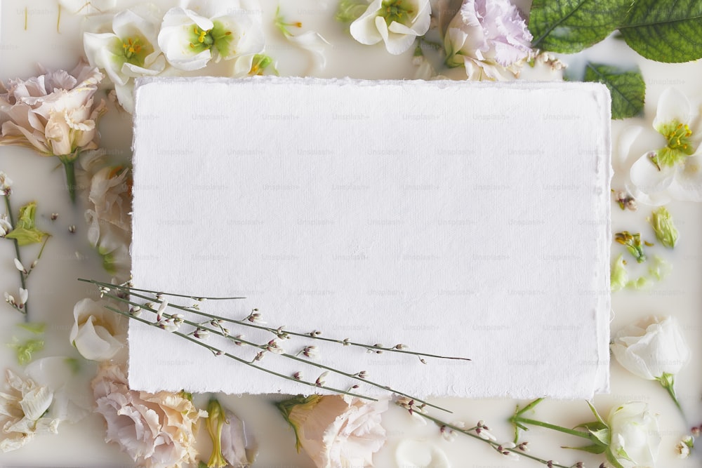 une feuille de papier blanche entourée de fleurs