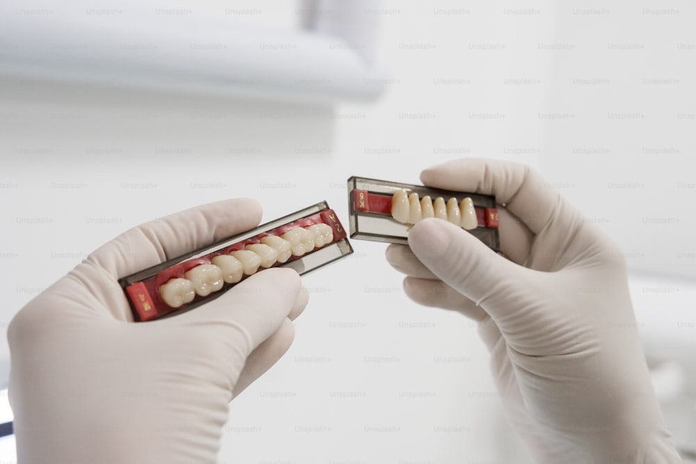 a pair of hands in gloves holding a box of teeth