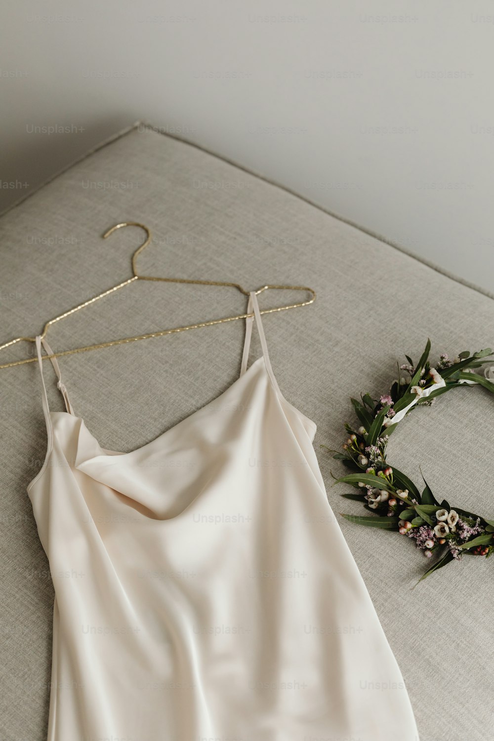 a dress hanging on a hanger next to a flower wreath