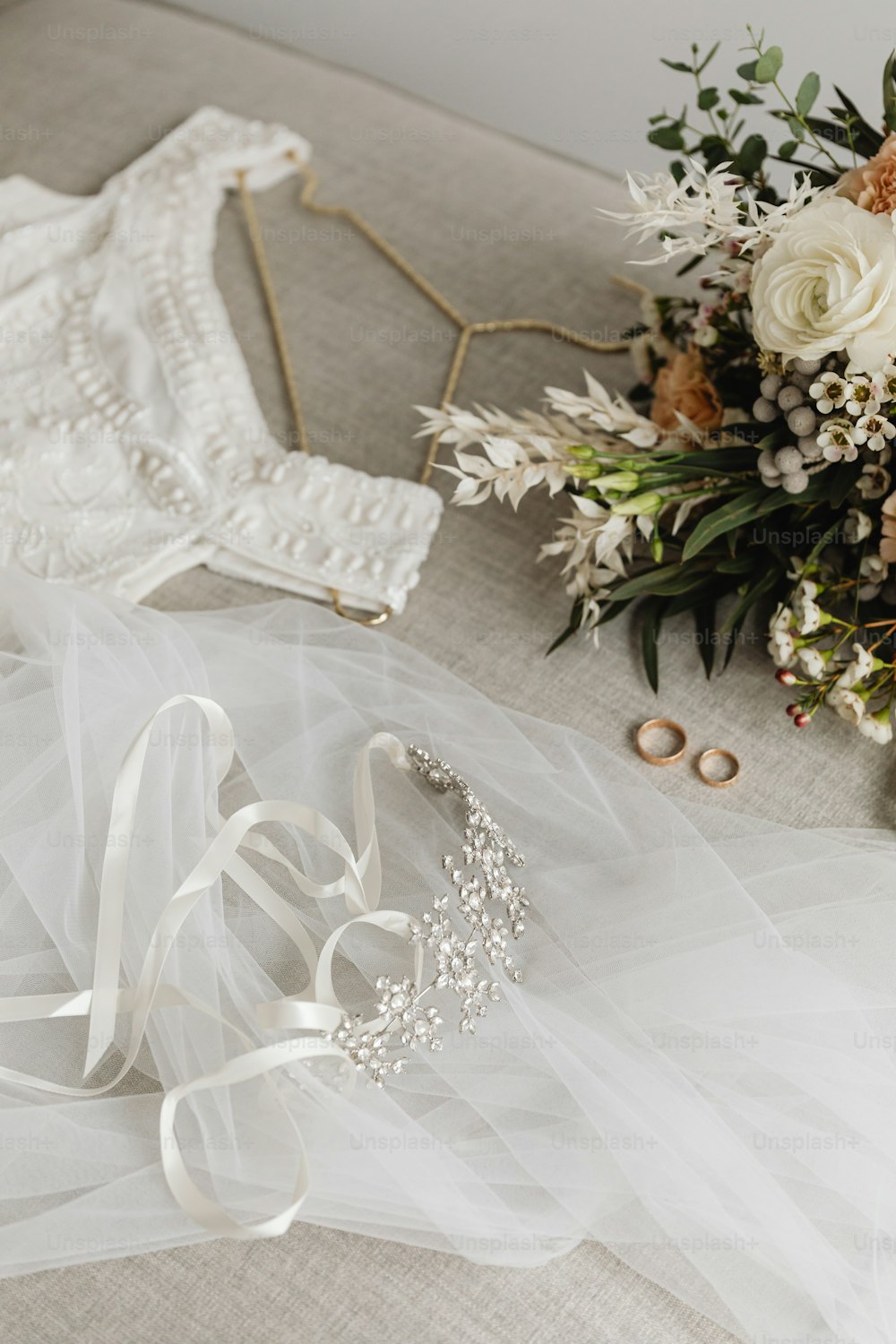 a bouquet of flowers and a wedding dress on a couch